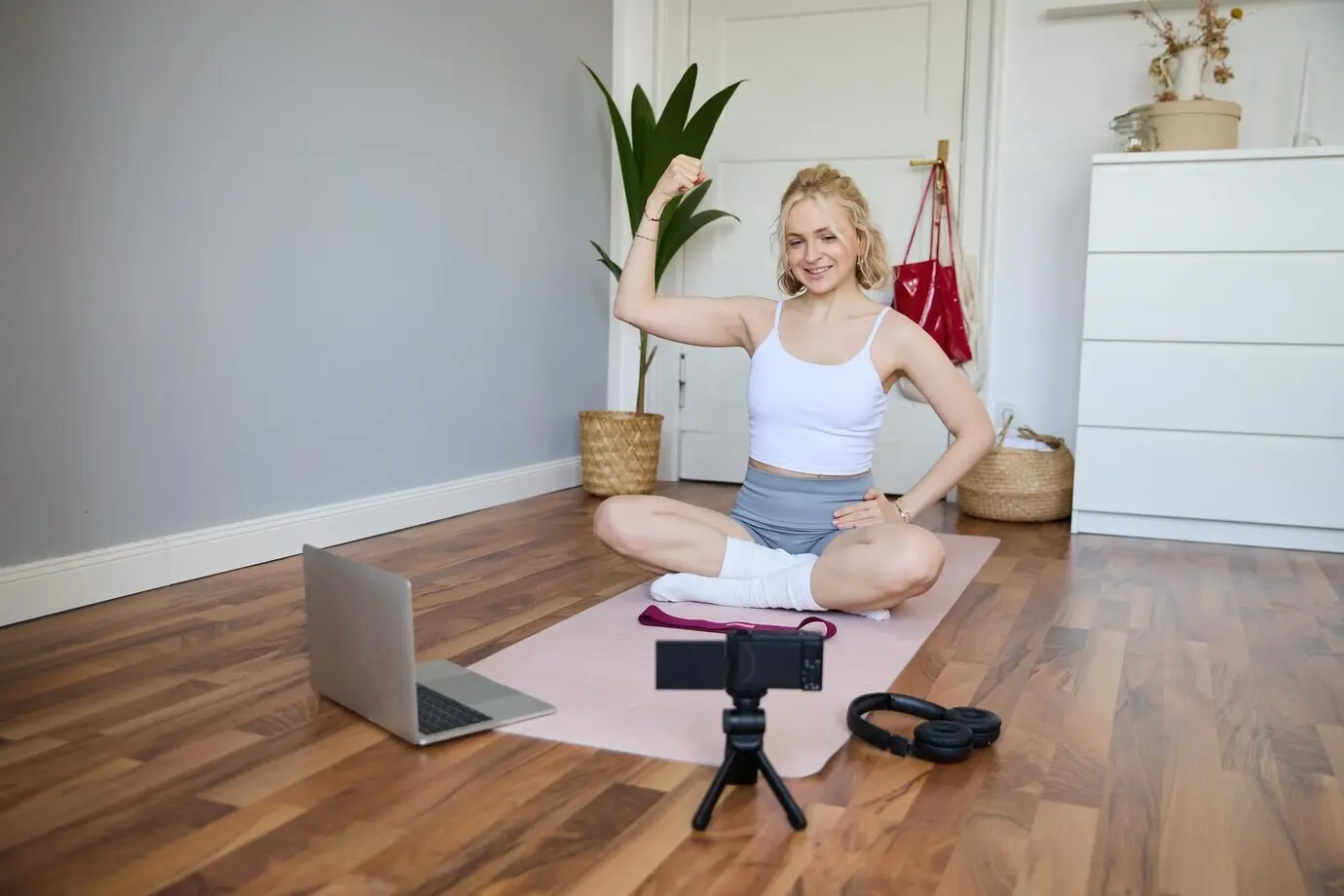 Porträt einer jungen weiblichen Athletin und Fitnesstrainerin, die eine Vlog-Trainingseinheit mit einer Digitalkamera aufnimmt.